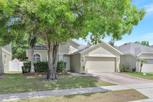 view of front of house featuring a front lawn, driveway, stucco siding, and fence