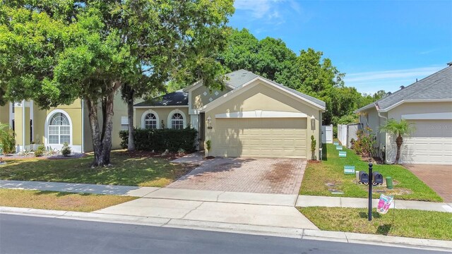 view of front of home with driveway, stucco siding, an attached garage, and a front lawn
