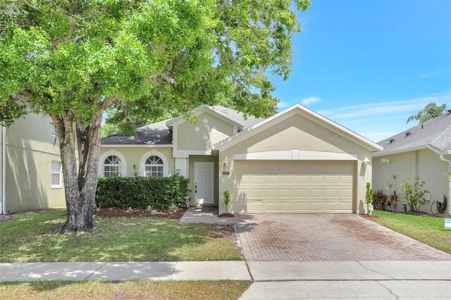 single story home featuring stucco siding, driveway, a garage, and a front lawn