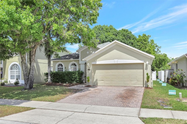 view of front of property featuring stucco siding, a garage, a front yard, and decorative driveway