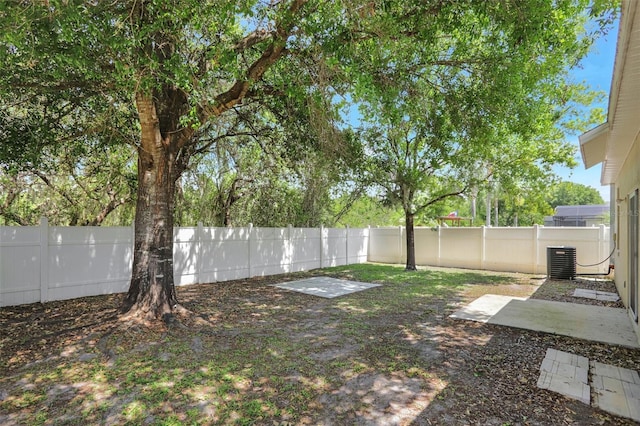 view of yard with a fenced backyard and central AC unit