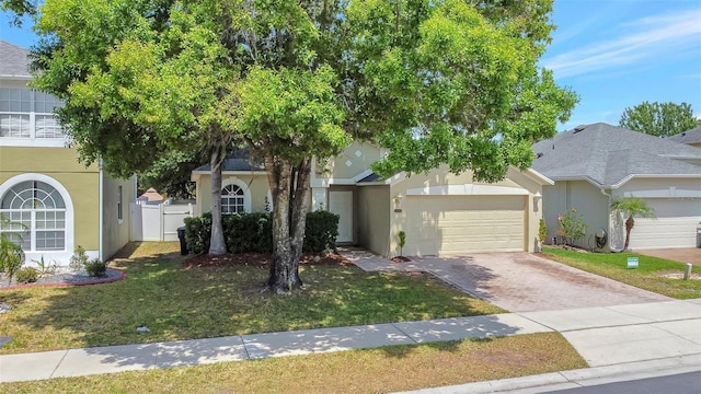view of front of property with a front lawn, decorative driveway, stucco siding, and an attached garage