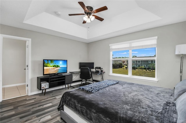 3661 Brighton Park Cir, Orlando, FL 32812 - bedroom featuring baseboards, a tray ceiling, wood finished floors, and a ceiling fan