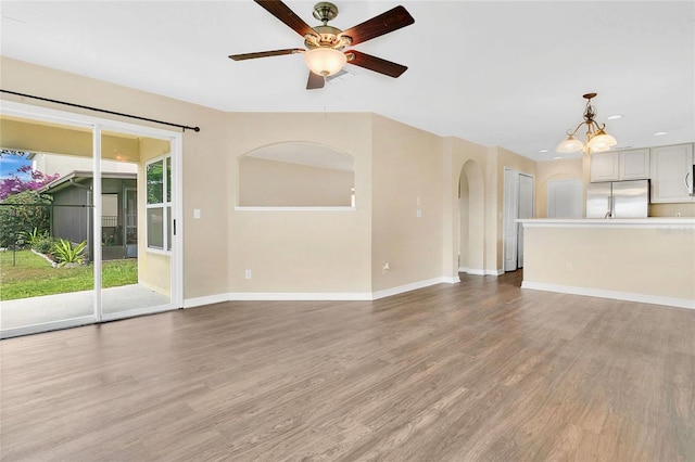 1556 Sherbourne St, Winter Garden, FL 34787 - unfurnished living room with arched walkways, ceiling fan with notable chandelier, baseboards, and light wood finished floors