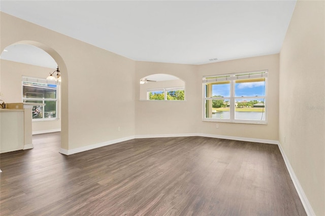 1556 Sherbourne St, Winter Garden, FL 34787 - empty room featuring baseboards, arched walkways, and dark wood-style flooring