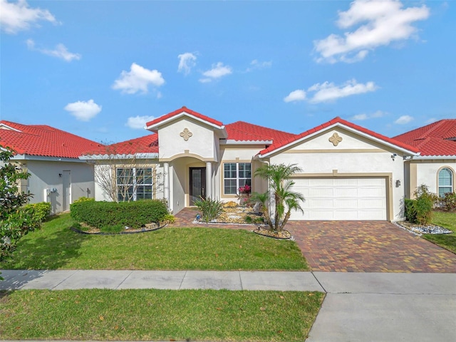 mediterranean / spanish-style house featuring driveway, a front yard, a tile roof, stucco siding, and an attached garage