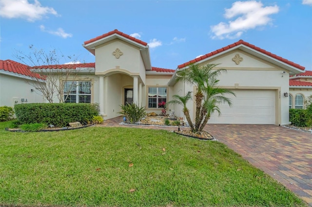 mediterranean / spanish-style home with a tile roof, stucco siding, decorative driveway, a front lawn, and a garage