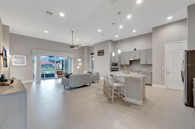 kitchen with open floor plan, a kitchen bar, backsplash, a sink, and visible vents