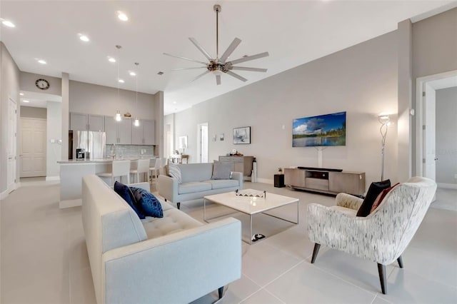 living area featuring a ceiling fan, a towering ceiling, light tile patterned floors, and recessed lighting