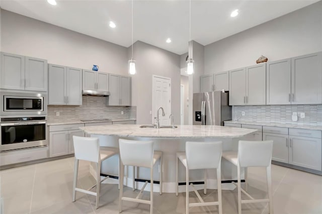 kitchen featuring under cabinet range hood, a sink, stainless steel appliances, and a kitchen breakfast bar