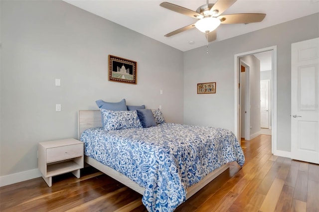 bedroom with a ceiling fan, baseboards, and wood finished floors
