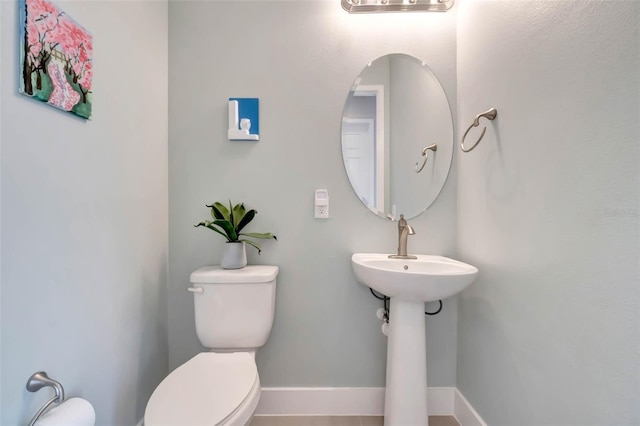 half bath featuring baseboards and toilet