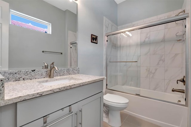 full bathroom with tile patterned floors, bath / shower combo with glass door, toilet, and vanity