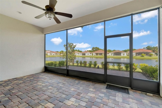 unfurnished sunroom with a ceiling fan and a water view