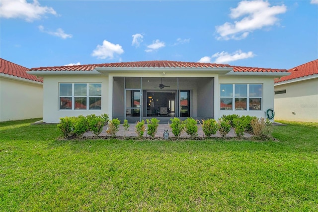 back of house with a lawn, stucco siding, a sunroom, and a tiled roof