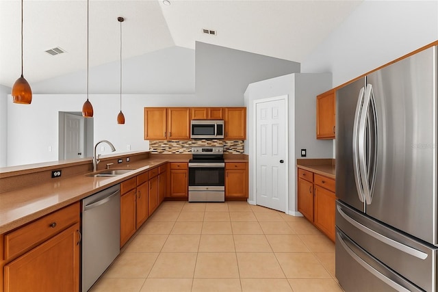 408 Magpie Ct, Kissimmee, FL 34759 - kitchen with stainless steel appliances, brown cabinets, pendant lighting, light tile patterned floors, and decorative backsplash