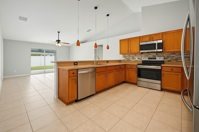 408 Magpie Ct, Kissimmee, FL 34759 - kitchen with stainless steel appliances, lofted ceiling, brown cabinets, backsplash, and a peninsula