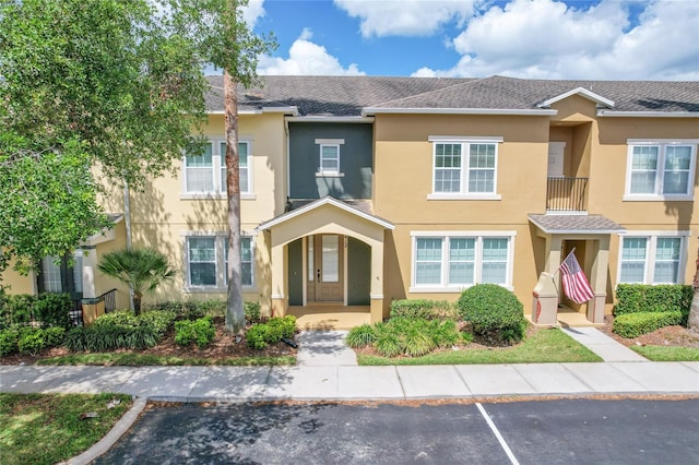 townhome / multi-family property with uncovered parking and stucco siding