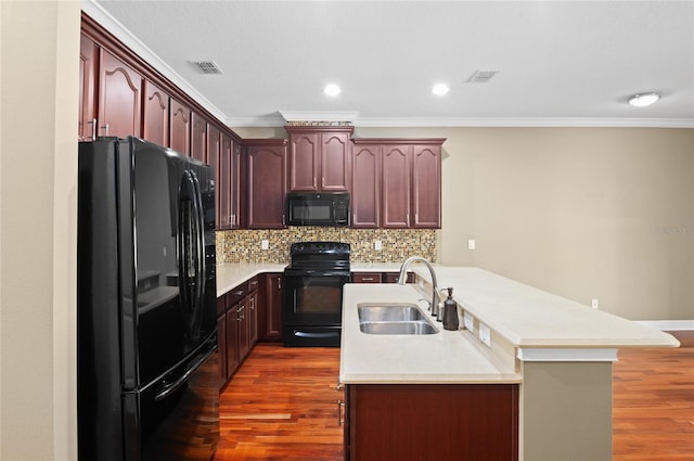 kitchen featuring visible vents, a sink, dark wood-type flooring, and black appliances