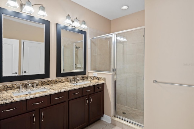 bathroom featuring tile patterned flooring, a sink, double vanity, and a stall shower