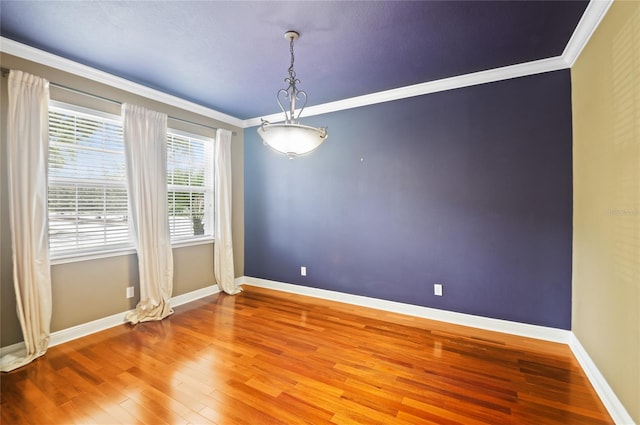 unfurnished room featuring baseboards, wood finished floors, and crown molding