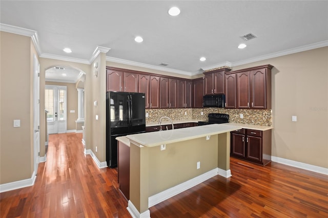 kitchen with arched walkways, dark wood finished floors, visible vents, and black appliances