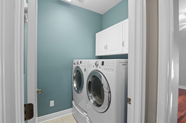 clothes washing area featuring baseboards, cabinet space, and washer and clothes dryer