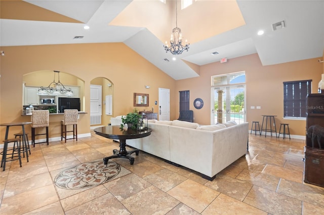 living room with stone tile floors, arched walkways, visible vents, and an inviting chandelier