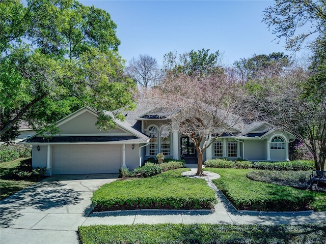 ranch-style house featuring an attached garage, concrete driveway, stucco siding, and a front lawn