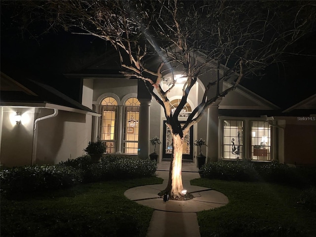 exterior entry at twilight featuring stucco siding