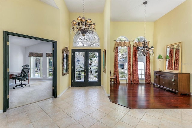carpeted entryway with french doors, plenty of natural light, a notable chandelier, and a towering ceiling