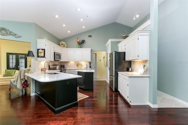 kitchen featuring white cabinets, a sink, appliances with stainless steel finishes, a peninsula, and lofted ceiling