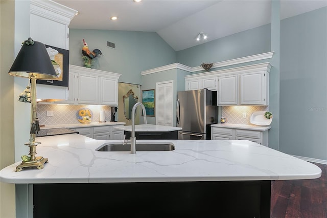 kitchen with freestanding refrigerator, light stone countertops, tasteful backsplash, a peninsula, and a sink