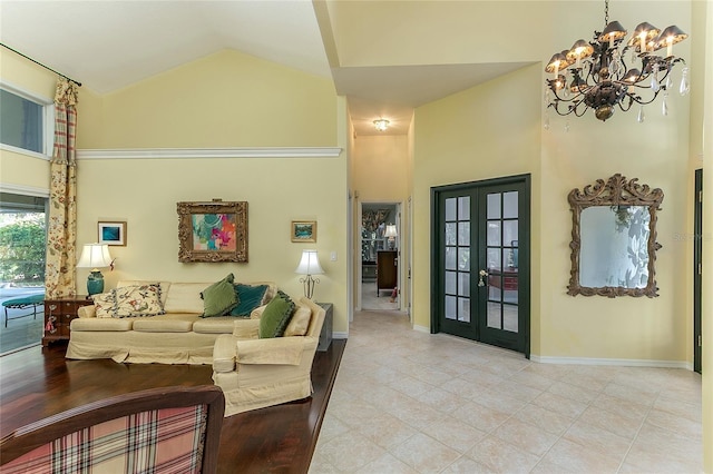 living area with high vaulted ceiling, an inviting chandelier, light tile patterned floors, french doors, and baseboards
