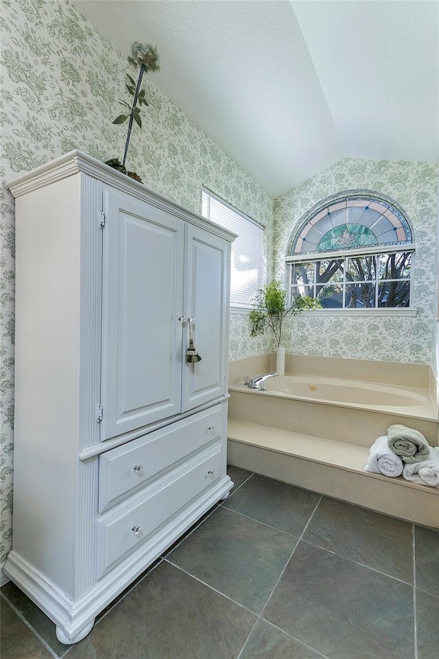 interior space with a bath, tile patterned floors, lofted ceiling, and wallpapered walls