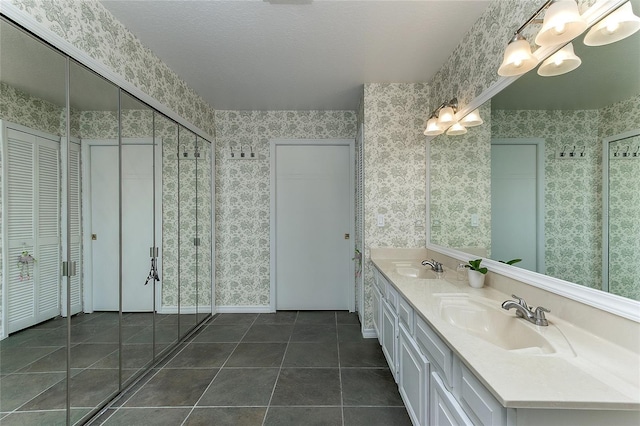 full bath with a sink, a closet, double vanity, and wallpapered walls