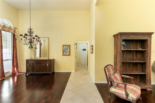 interior space with a notable chandelier, wood finished floors, a high ceiling, and baseboards