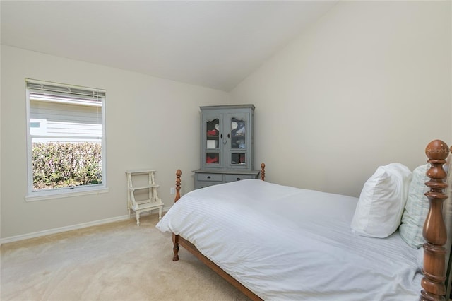 bedroom featuring light carpet, baseboards, and lofted ceiling