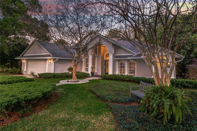 view of front facade with an attached garage, stucco siding, and a front lawn
