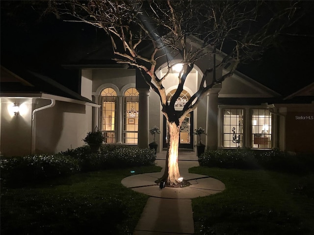 exterior entry at twilight with a yard, french doors, and stucco siding