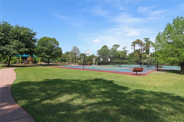 view of property's community featuring playground community, fence, community basketball court, and a lawn