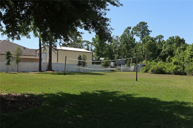 view of home's community featuring fence, volleyball court, and a lawn