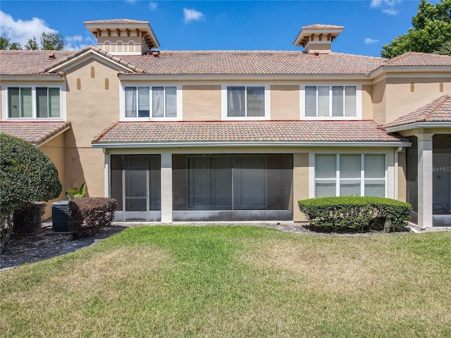 rear view of house with a tiled roof, a sunroom, stucco siding, and a yard