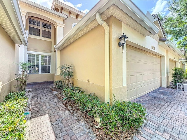 view of home's exterior with stucco siding, a garage, and decorative driveway