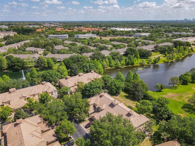 aerial perspective of suburban area with a nearby body of water and a tree filled landscape