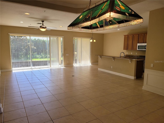unfurnished living room featuring a ceiling fan, light tile patterned flooring, recessed lighting, and a sink