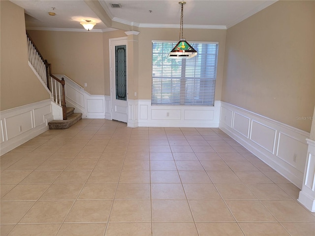 unfurnished dining area featuring a decorative wall, ornamental molding, wainscoting, light tile patterned floors, and decorative columns