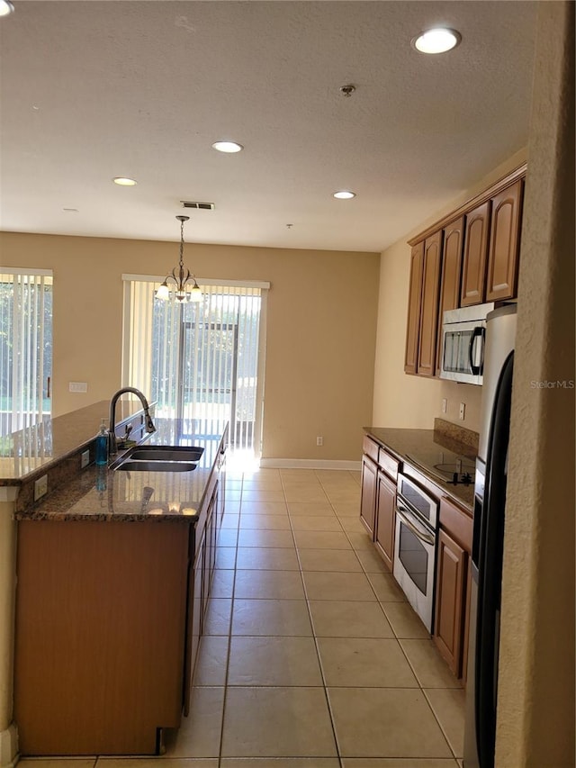 kitchen with stainless steel appliances, a sink, recessed lighting, light tile patterned floors, and baseboards