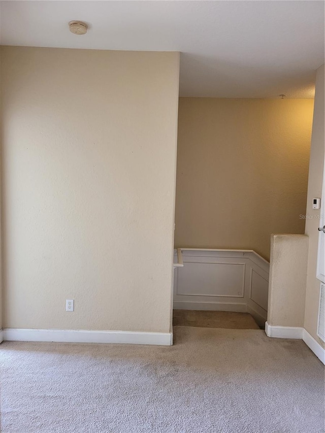 unfurnished room featuring light carpet, a smoke detector, and baseboards