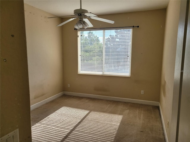 empty room with ceiling fan, light colored carpet, and baseboards